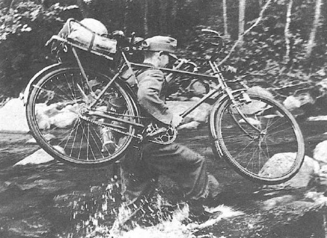 Gebirgsjäger cruzando un río con una bicicleta a cuestas